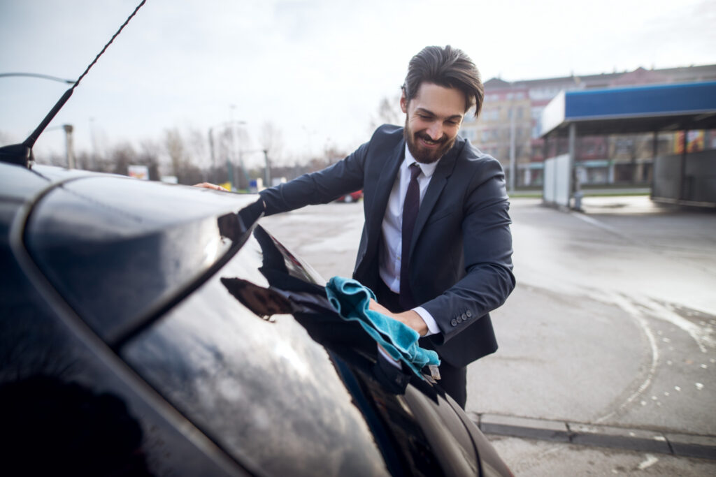 Man cleaning light dust from a car after skipping washing for several days