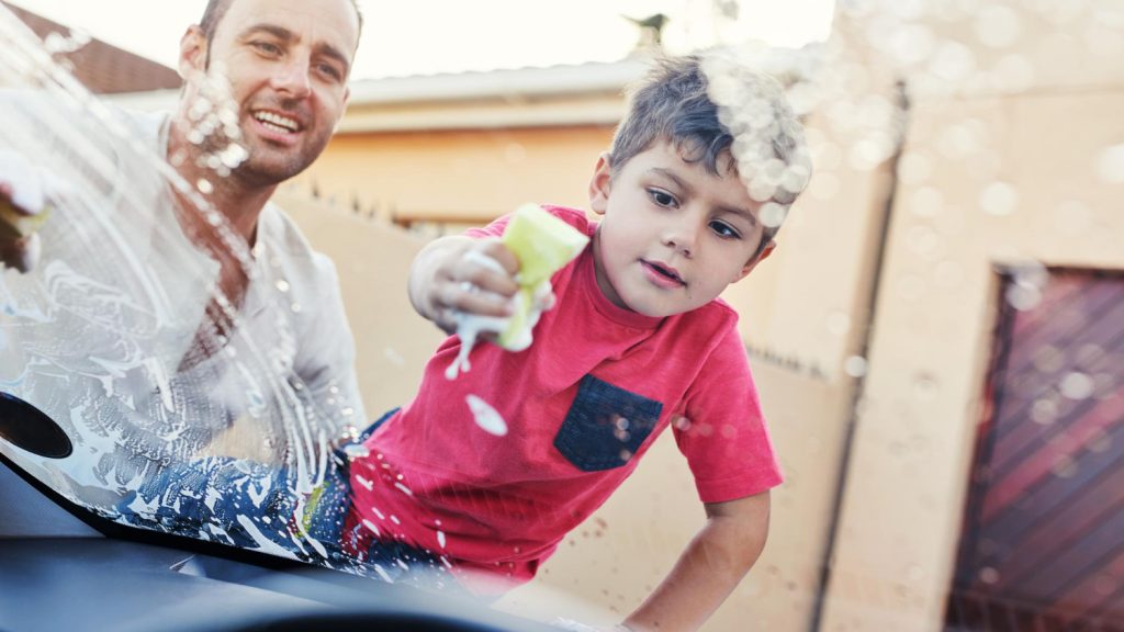 Child spraying detergent on windshield