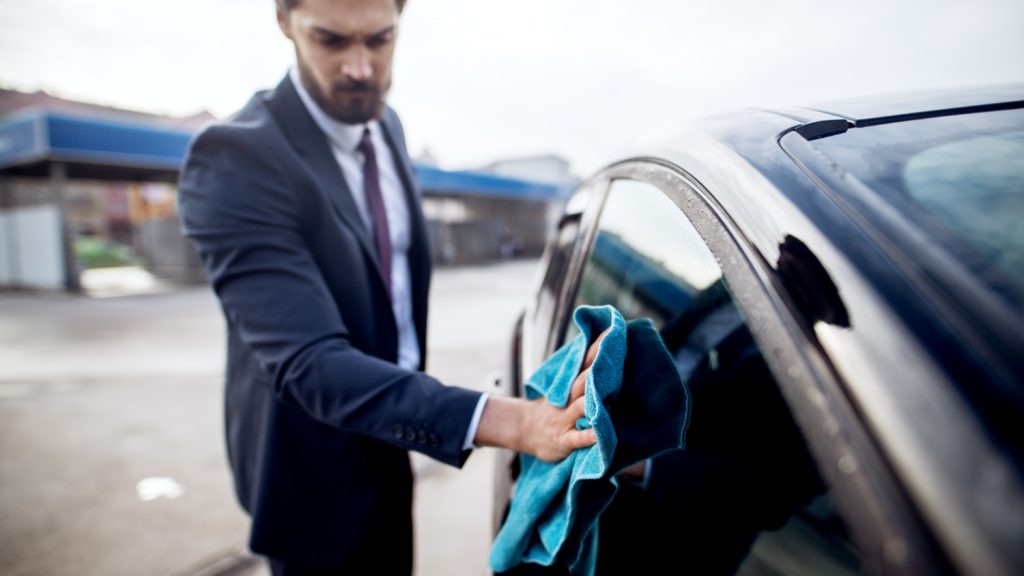 Car owner wiping dust from the car to check how dirty the surface has become